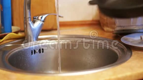 女人在家庭厨房里用自来水清洗一个热烤锅慢动作视频的预览图