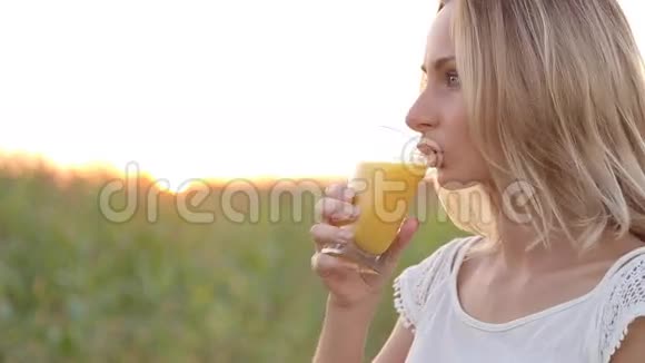 年轻女子在外面喝橙汁视频的预览图