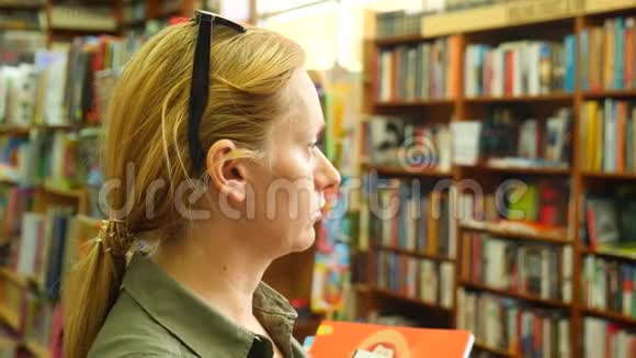 一个女人站在图书馆的肖像背景的书架4k慢镜头视频的预览图