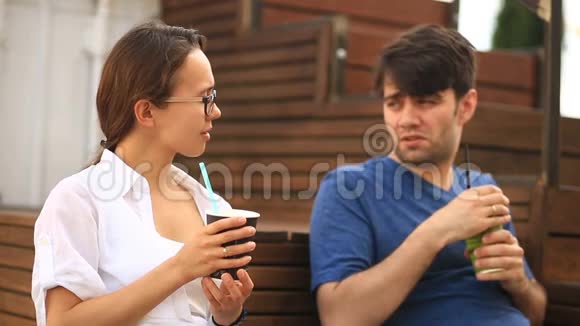 一对男人和一个女孩正在非正式的户外咖啡馆里喝咖啡和聊天快餐视频的预览图