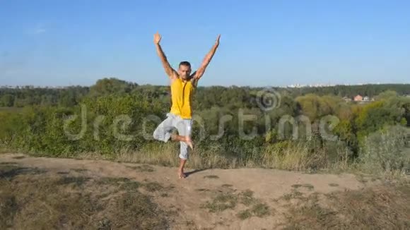 年轻的运动男子站在树瑜伽姿势户外在大自然中练习瑜伽动作和姿势的白人Yogi视频的预览图