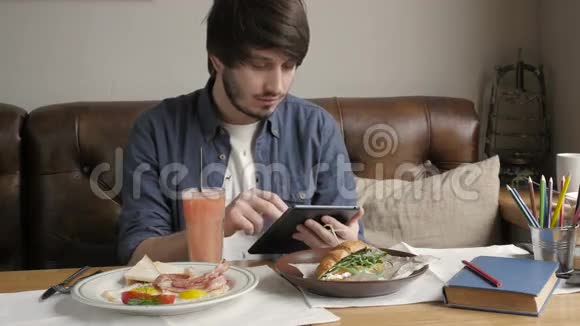 年轻时尚人士嬉皮士在城市咖啡厅喝咖啡在午餐时间和工作平板电脑视频的预览图