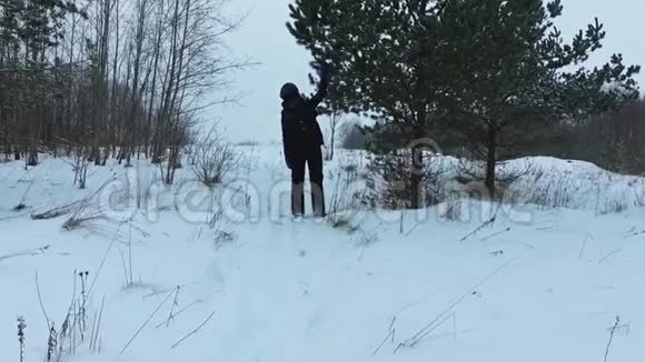 一位年轻女子在降雪时行走的慢速后视斯坦迪卡姆视频的预览图