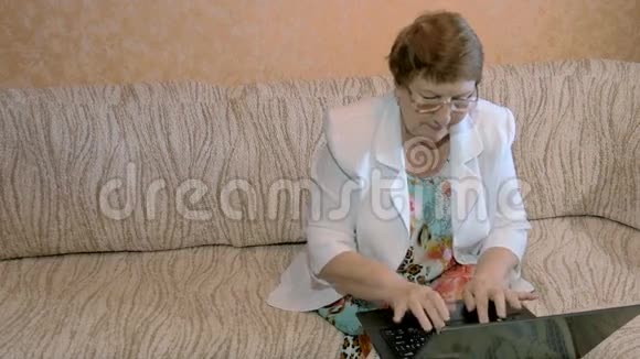 一个年纪大的女人在家里用笔记本电脑工作视频的预览图