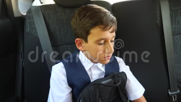 那个悲伤的男孩穿着校服坐在车里4k慢镜头视频的预览图