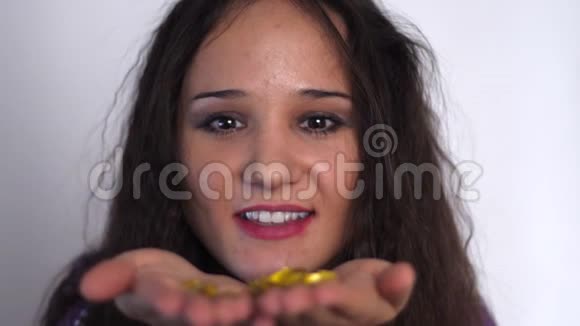 年轻美丽的黑发女子慢动作吹着金色的闪光视频的预览图
