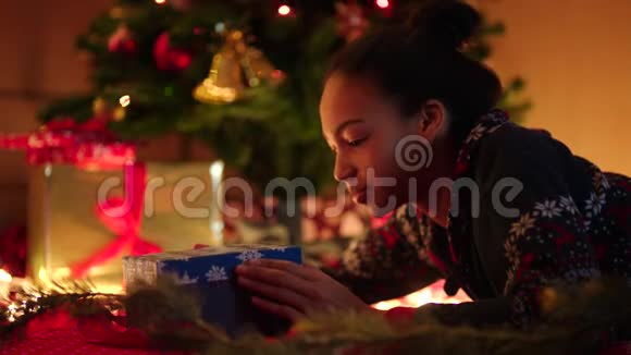 黑人少女在装饰圣诞树下打开圣诞礼物盒视频的预览图