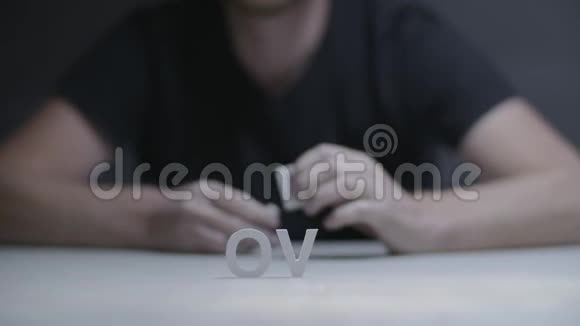 男性的双手由白色字母组成灰色背景下的爱视频的预览图