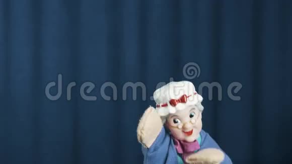 老女人手偶出现在现场蓝色背景上流畅的舞蹈动作视频的预览图