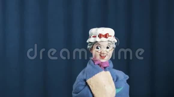 老女人手偶摇摇头积极地在蓝底上跳舞视频的预览图