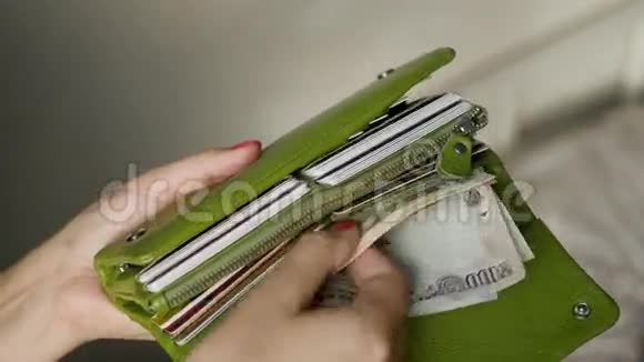 一个穿着粉色指甲的女孩用信用卡和来自不同国家的钱打开她的绿色钱包钱数20美元视频的预览图