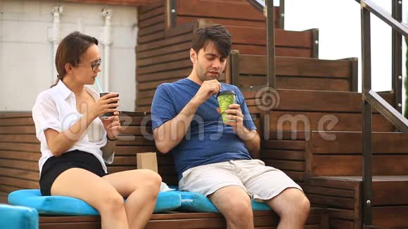 一对男人和一个女孩正在非正式的户外咖啡馆里喝咖啡和聊天快餐视频的预览图