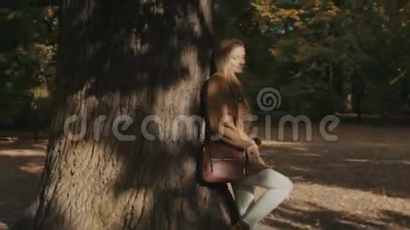 年轻的金发女孩在阳光明媚的秋天公园享受美丽的一天视频的预览图