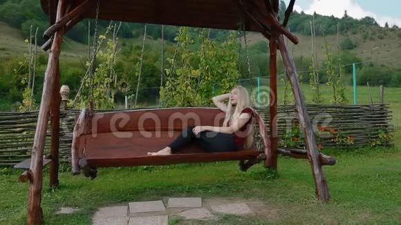 年轻女子在大木秋千上休息视频的预览图