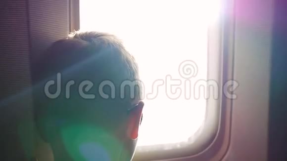 阳光明媚的一天一个孩子望着窗外的飞机视频的预览图