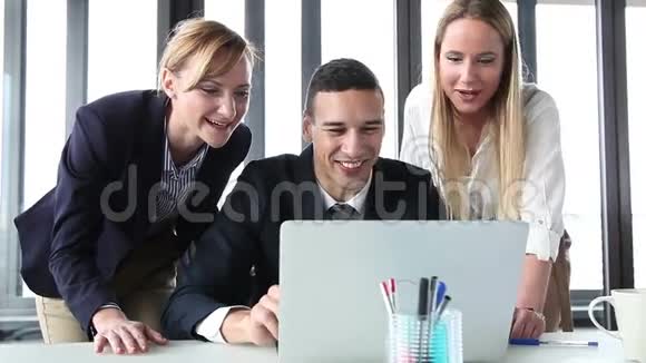 年轻的经理和两个带手提电脑的女商人热情洋溢欢呼雀跃视频的预览图