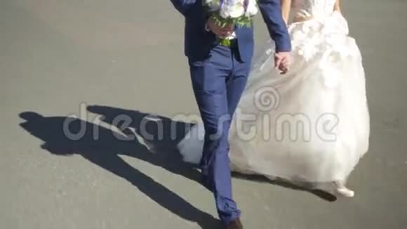 年轻的新郎牵着新娘的手走着新娘走在街上手牵着登记处附近的手视频的预览图
