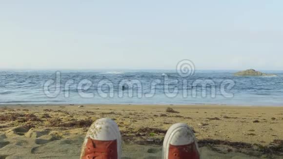 红色运动鞋放松在野生海滩与蓝色波浪海洋背景视频的预览图