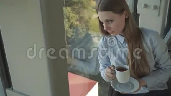 女孩在时尚餐厅的窗户边喝茶视频的预览图