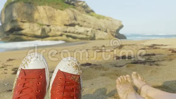 红色运动鞋放松在野生海滩与蓝色波浪海洋背景视频的预览图