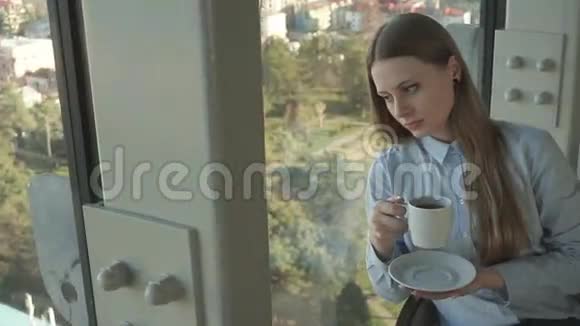 女孩在时尚餐厅的窗户边喝茶视频的预览图