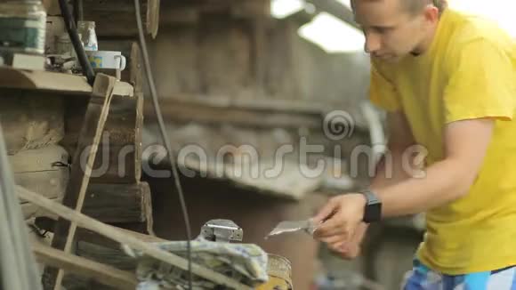 年轻人用虎钳挤压金属部分在一座乡村别墅的背景下视频的预览图