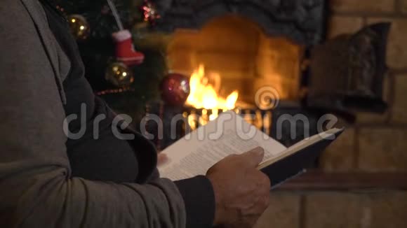 圣诞前夜老人在壁炉和圣诞树附近看书视频的预览图
