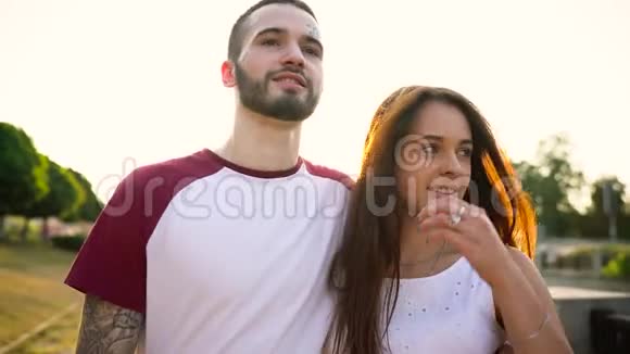 一对相爱的年轻夫妇日落时分在街上散步视频的预览图