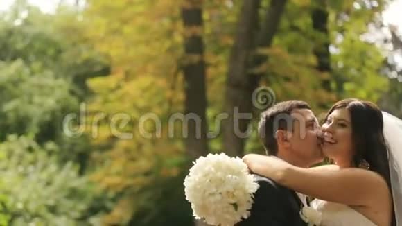新婚的新娘和新郎高兴地接吻意识到他们现在结婚了以夏季公园为背景的室外拍摄视频的预览图