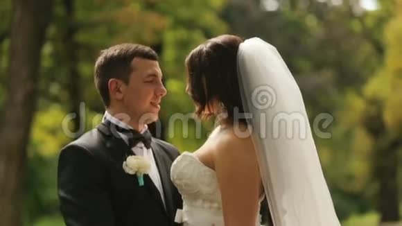 开朗刚结婚的新娘和新郎要接吻以夏季公园为背景的室外拍摄视频的预览图