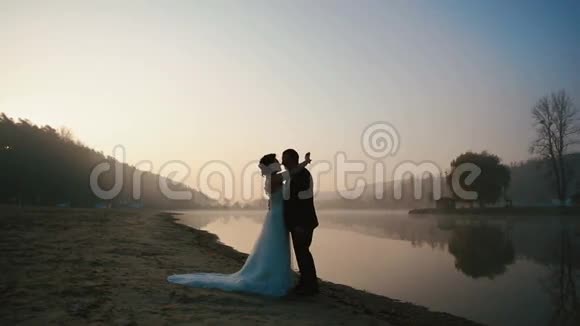 婚礼当天晚上两对新婚夫妇在日落的浪漫湖上进行甜蜜的交谈和亲吻视频的预览图