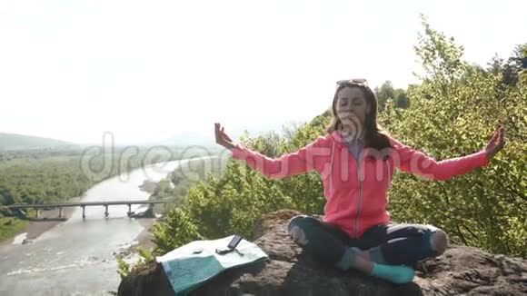 年轻活跃的女孩通过在山岩练习瑜伽放松宽河谷作为背景视频的预览图