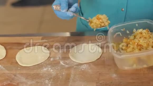 面包师厨师在蛋糕店的木桌上烤饼前把面团填平视频的预览图