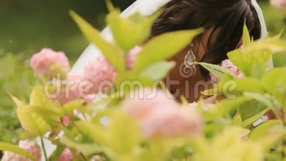在阳光明媚的花园里散发着粉红色花朵的新娘视频的预览图