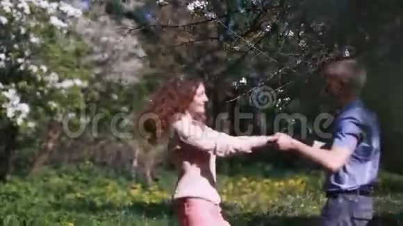 快乐的激情夫妇在盛开的樱桃园开着许多白花年轻漂亮的女孩在旋转视频的预览图