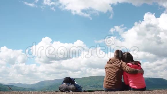 年轻迷人的旅游情侣在令人惊叹的蓝天背景下拥抱和亲吻视频的预览图