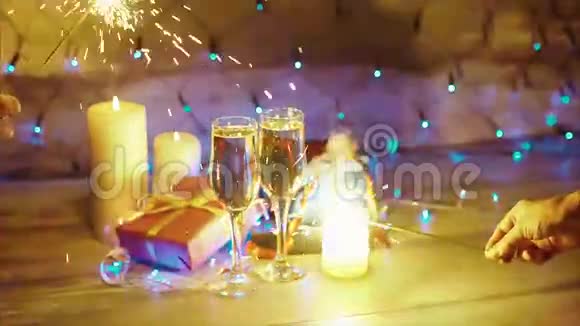 在圣诞礼物蜡烛和香槟的背景下手拿着火花视频的预览图