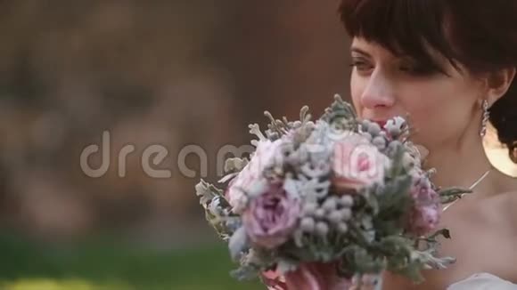体贴的新娘在户外捧着一束粉红色的玫瑰花从相机旁眺望视频的预览图