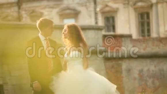 浪漫的吻华丽的新婚夫妇在阳光公园附近的老式巴洛克宫殿视频的预览图