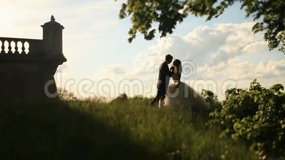 浪漫的吻新婚夫妇在日落公园附近的复古建筑与栏杆视频的预览图
