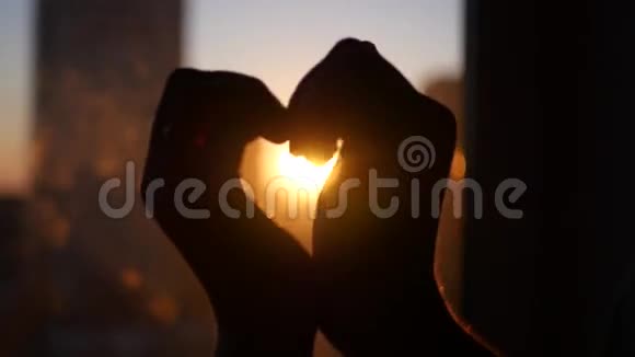 情侣们在美丽的黄色背景下双手捧出一颗心在城堡里交叉手指视频的预览图