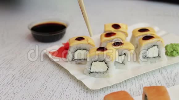 寿司是用中国棍子拿的浸泡在酱油里美味的寿司和三文鱼姜奶酪和芥末视频的预览图