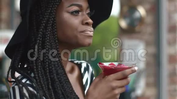 穿着黑色帽子和条纹时尚连衣裙酒吧里带着清凉鸡尾酒的贴心体贴的非裔美国女士视频的预览图