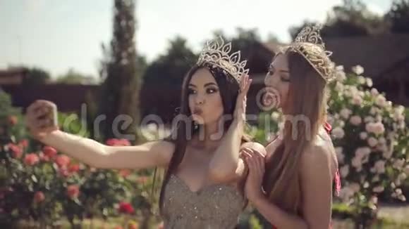 两个穿着晚礼服和皇冠的女孩自拍视频的预览图
