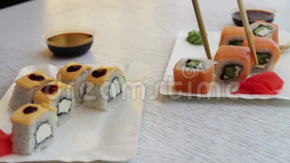 寿司是用中国棍子拿的浸泡在酱油里美味的寿司和三文鱼姜奶酪和芥末视频的预览图