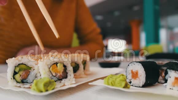 女孩坐着拿着木棍桌子上的咖啡馆里的寿司是寿司日本菜视频的预览图