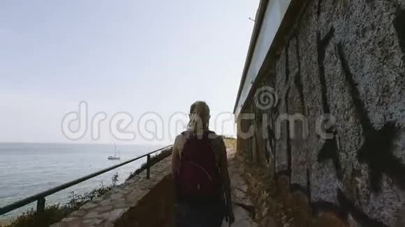旅游妇女在春天去地中海国家旅游女孩走在石路上带着大海视频的预览图