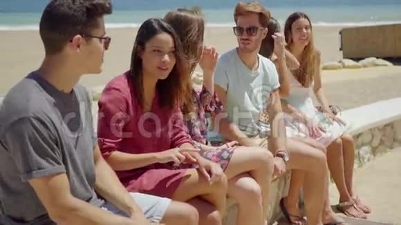 穿短裤的青少年朋友在海滩边聊天视频的预览图