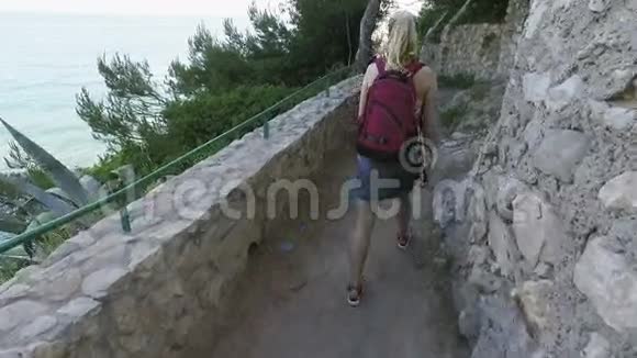 旅游妇女在春天去地中海国家旅游女孩走在石路上带着大海视频的预览图