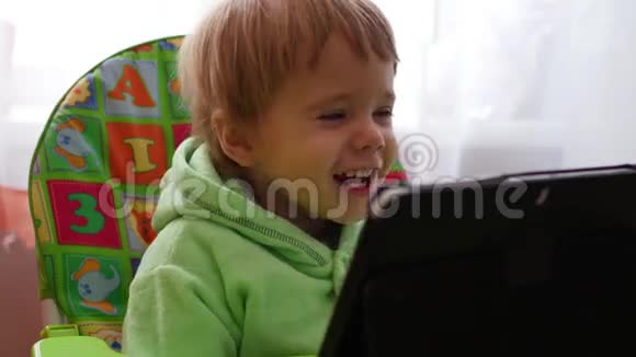 快乐的孩子在平板上看动画片微笑着视频的预览图